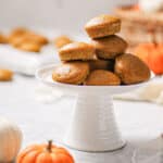 Mini pumpkin muffins stacked in a pyramid shape on top of a white cake stand.