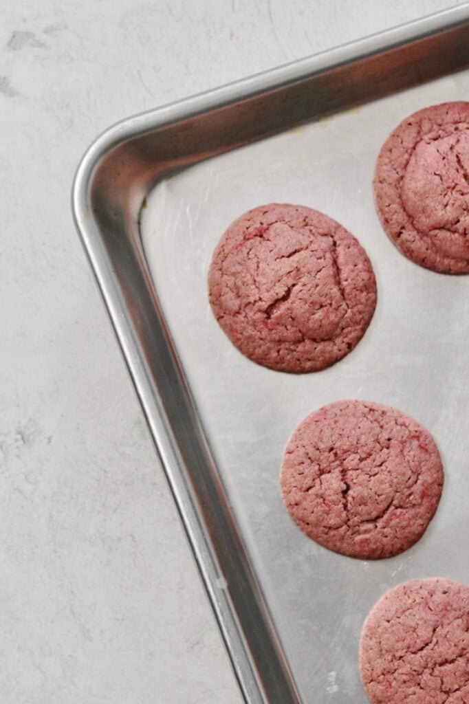 overhead image of pink sugar cookies sitting on metallic cookie sheet