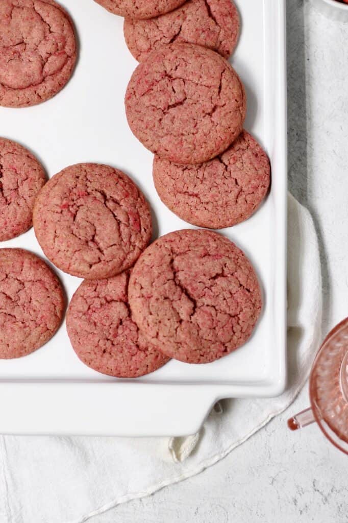 overhead image of pink sugar cookies sitting on a white plate