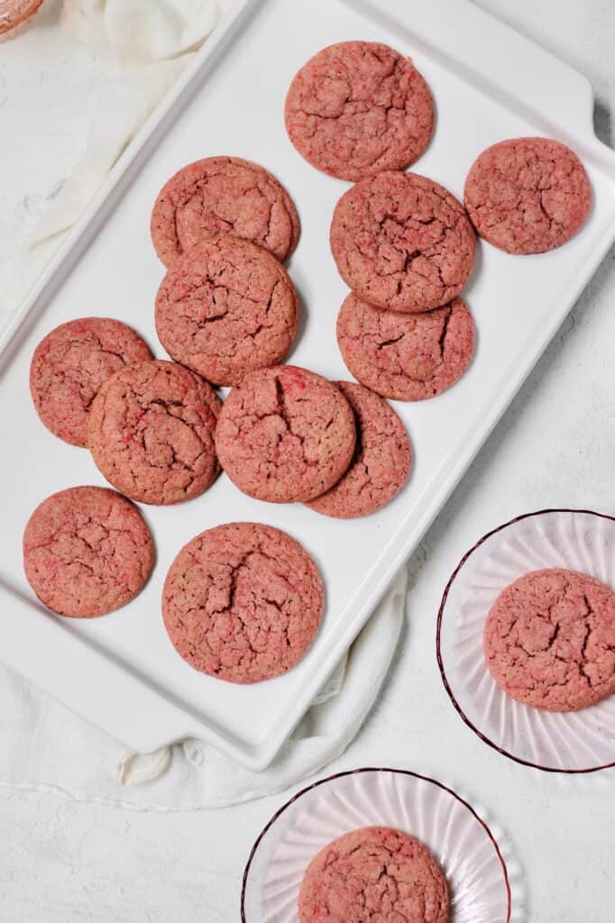 overhead image of pink sugar cookies sitting on a white plate