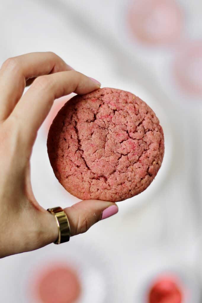 holding a pink sugar cookie close to the camera
