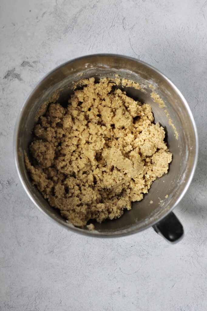 crumbly dough mixture after combining flour and eggs in mixing bowl for brown sugar cookies