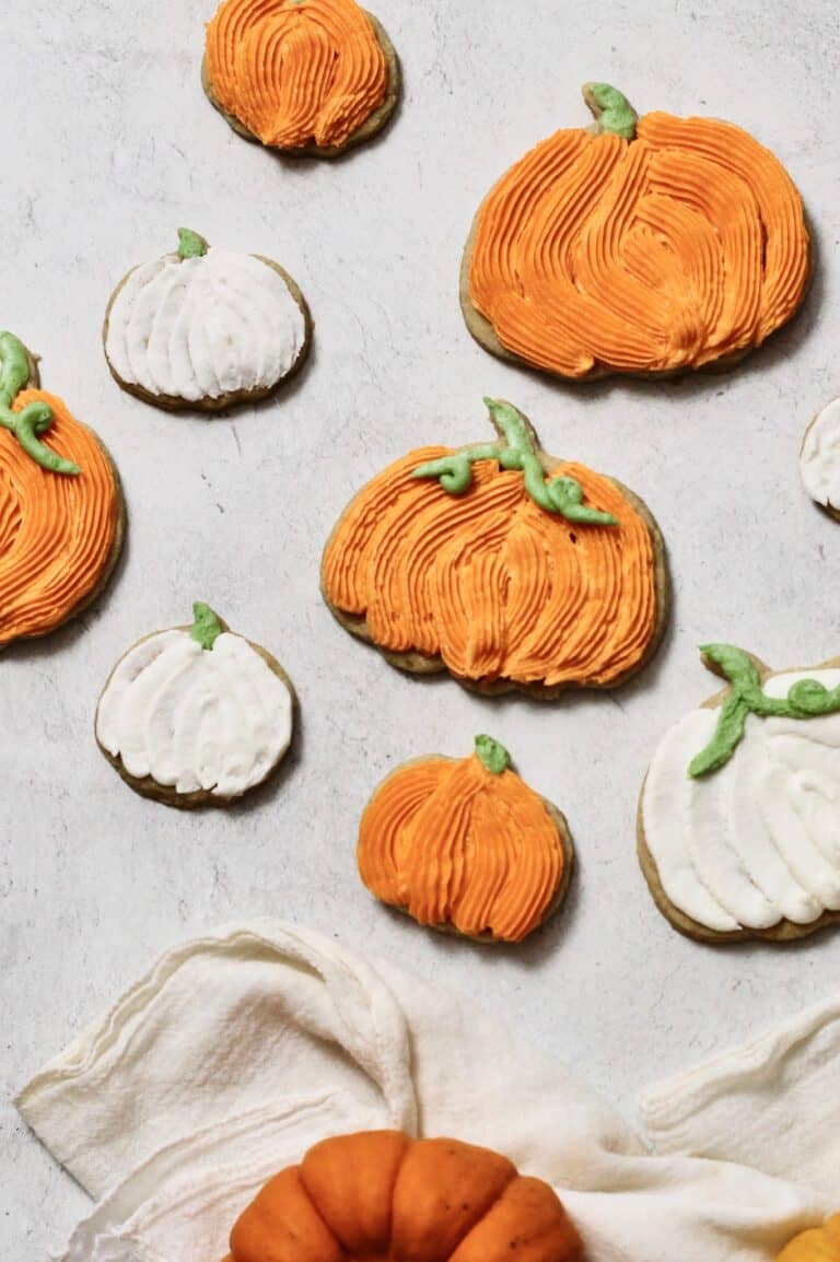 fully decorated pumpkin cookies, coated in orange and white buttercream