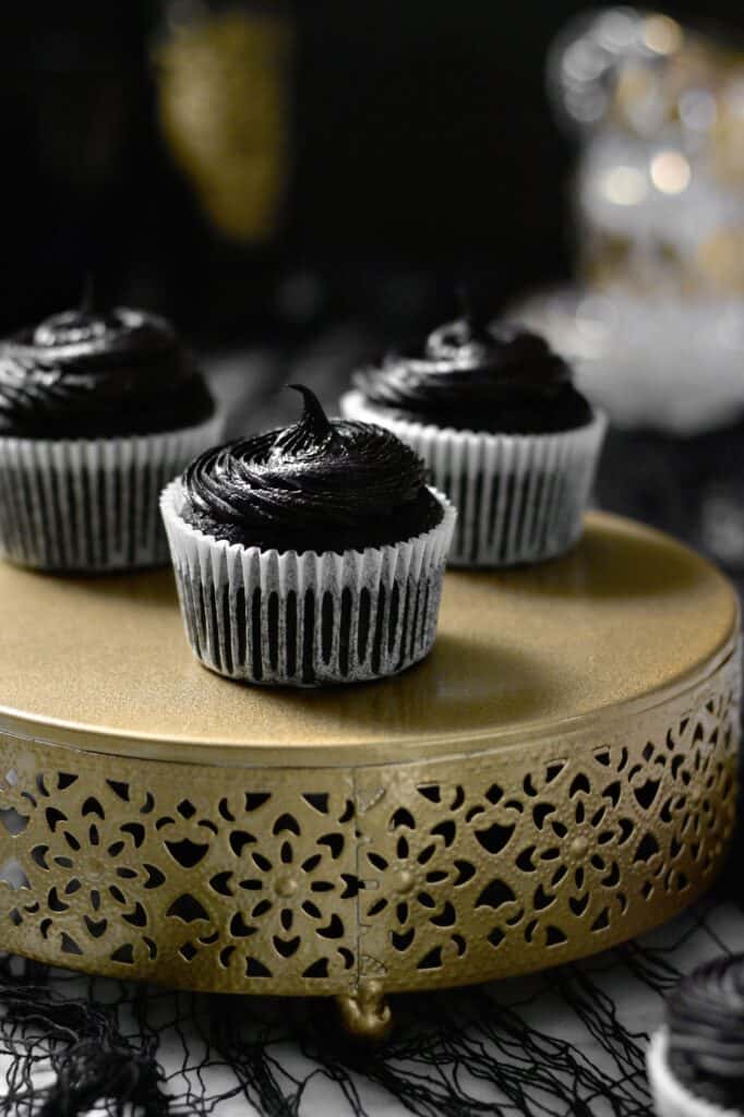 black cocoa cupcakes, sitting on a gold cake stand