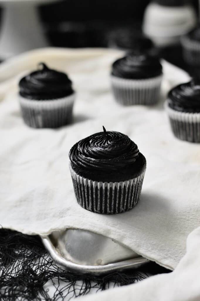 black cupcakes, sitting on white linen