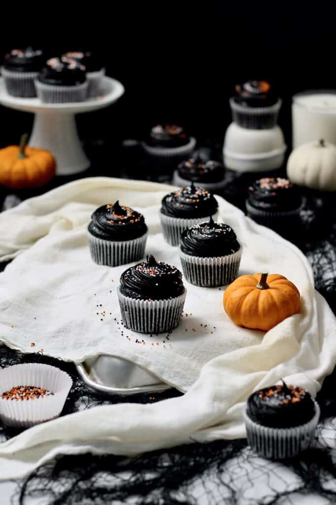 black cocoa cupcakes, sitting on a white linen material in front of a black background