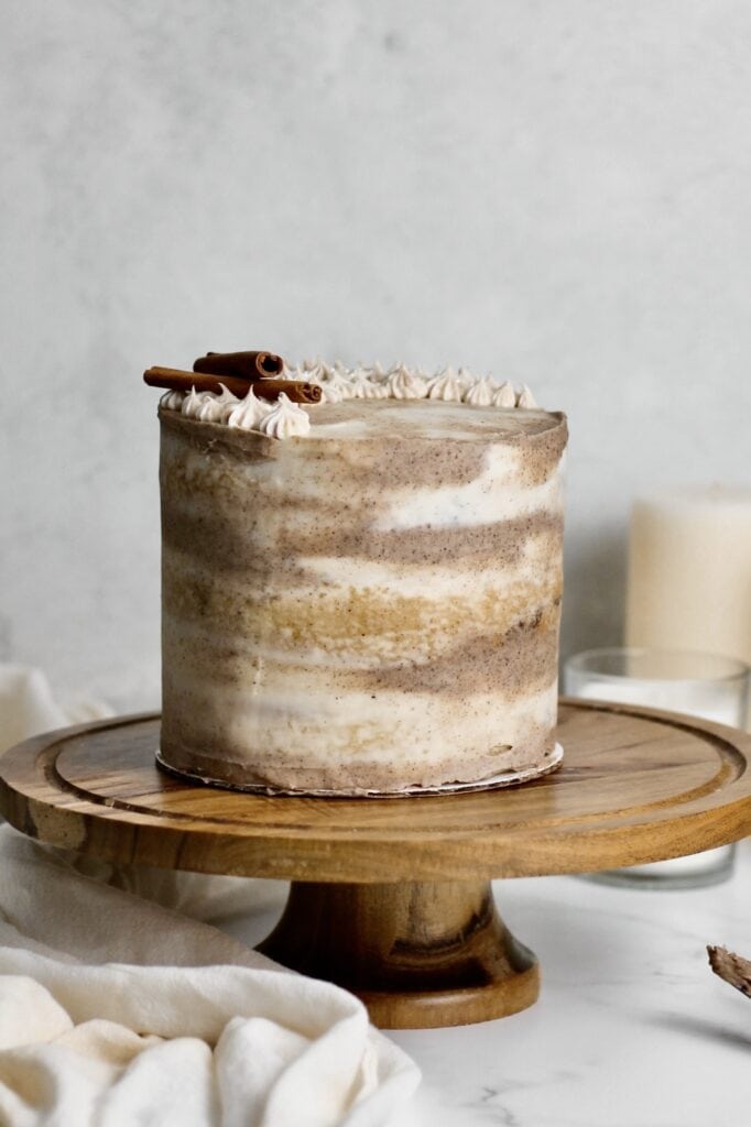 dirty chai spice cake, coated in marbled frosting and sitting on a wooden cake stand