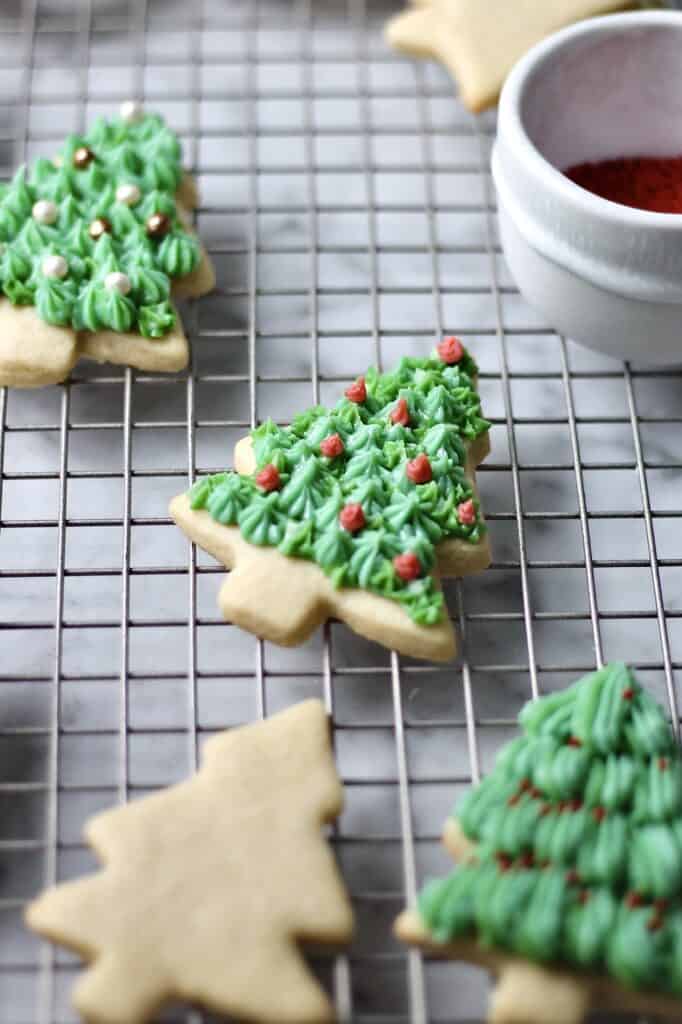a few decorated Christmas tree sugar cookies sitting on a cooling rack
