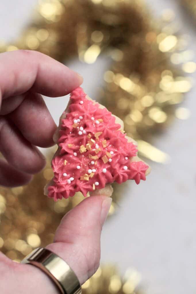 one of many mini Christmas tree sugar cookies, decorated with sprinkles and pink buttercream