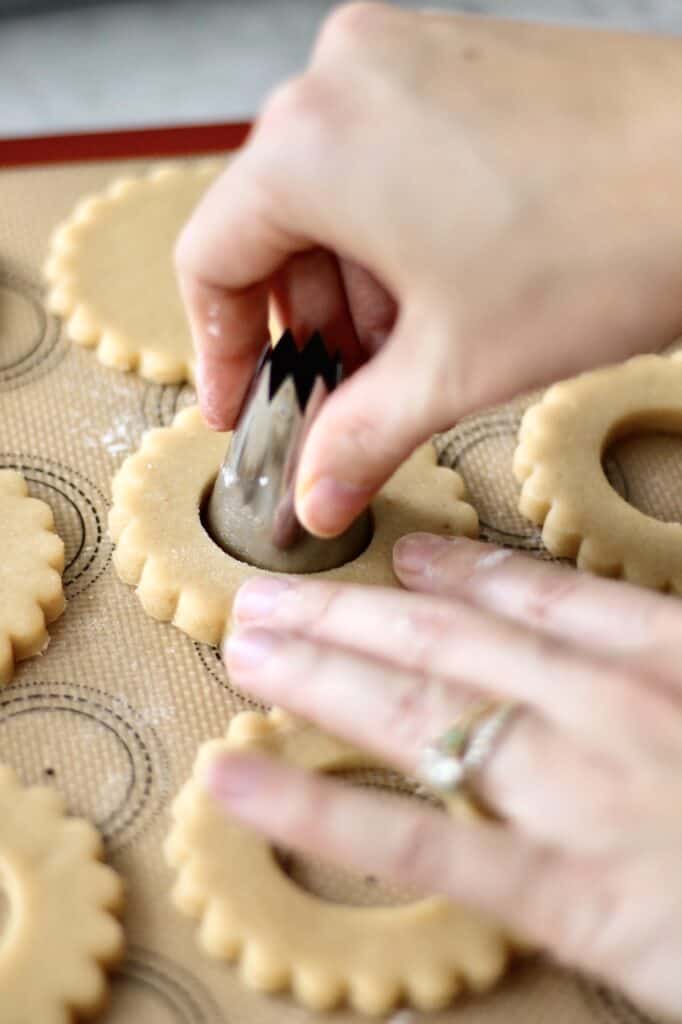 cutting out the center of wreath sugar cookies with a large piping tip