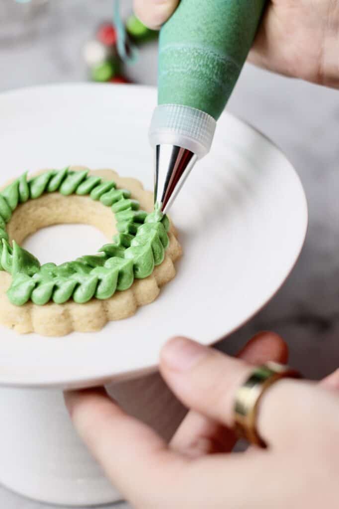piping Christmas wreath sugar cookies with a leaf tip