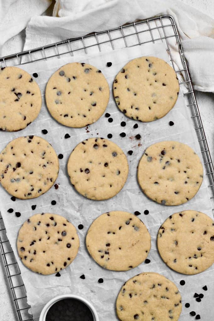 overhead image of baked chocolate chip sugar cookies on a wire rack with parchment paper behind them