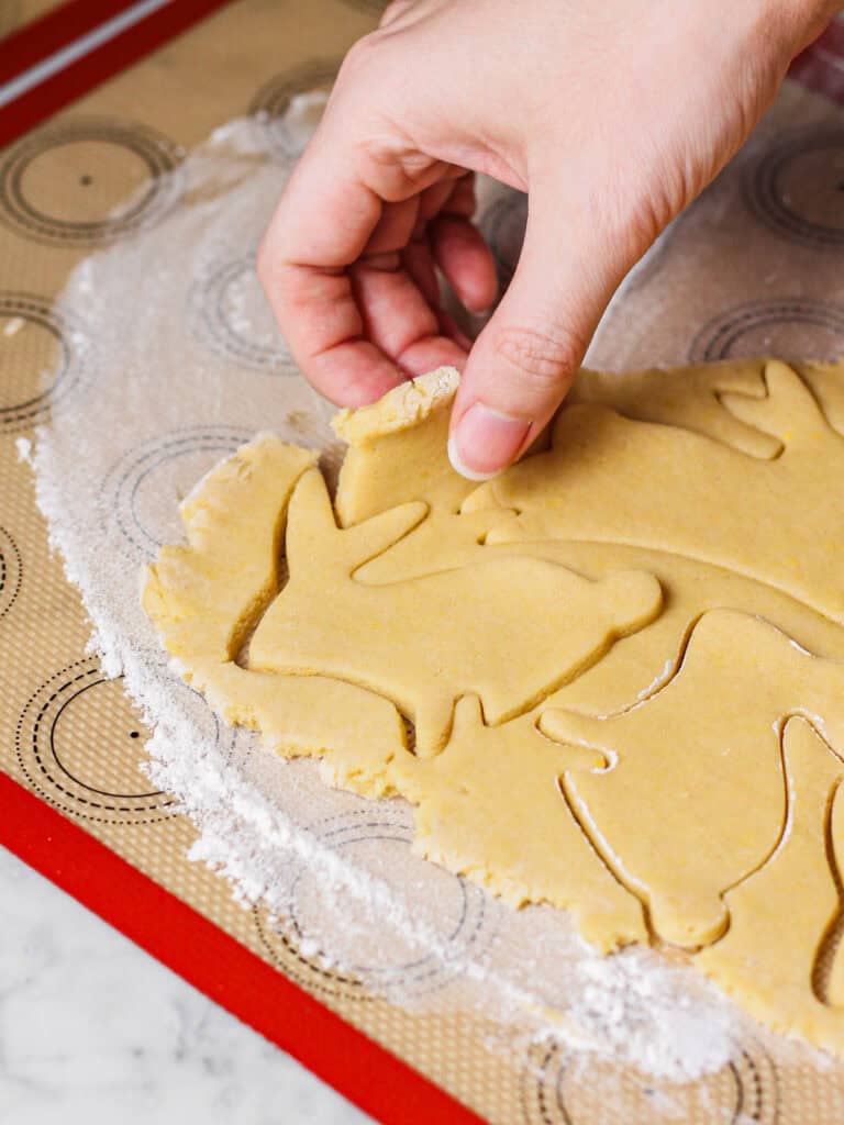 Peeling away dough from a Easter bunny sugar cookies.