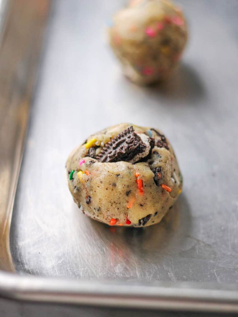 Oreo funfetti cookie dough balls sitting on a baking sheet.