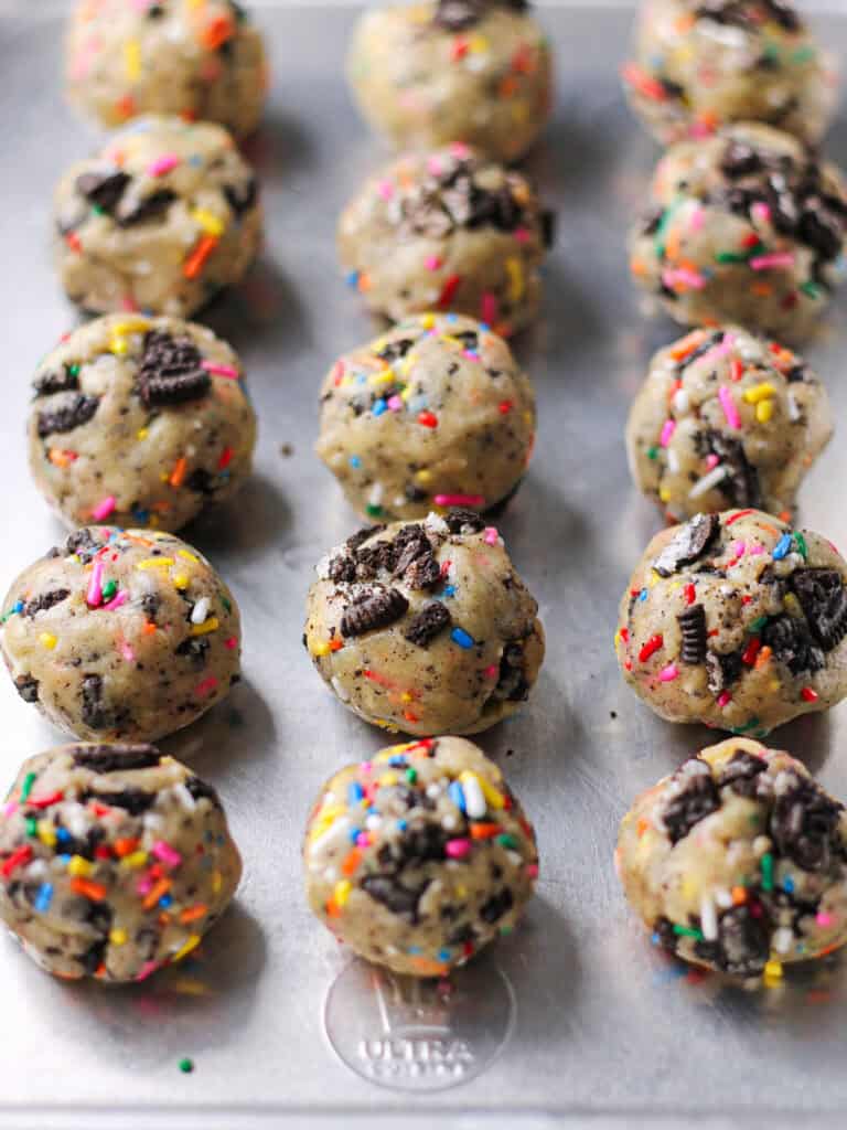 Oreo funfetti cookie dough balls sitting on a baking sheet.