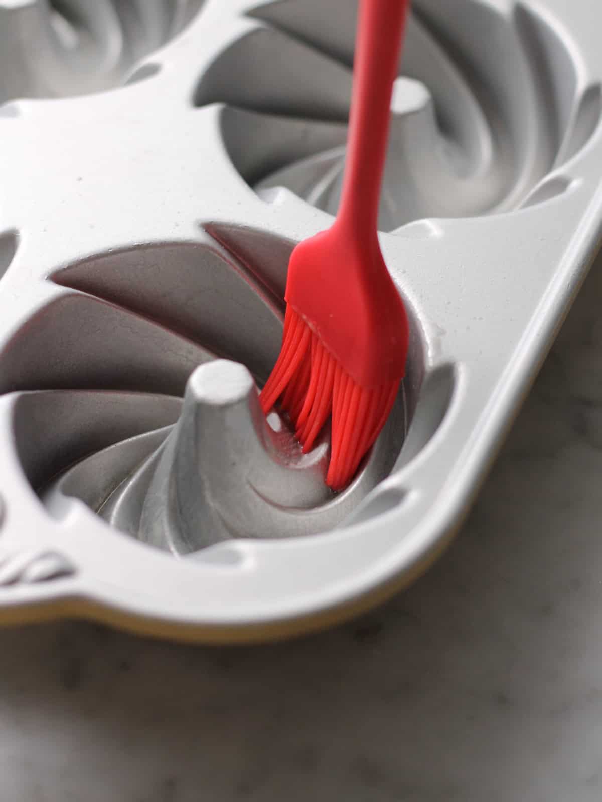 Preparing a mini Bundt pan to add batter to it.