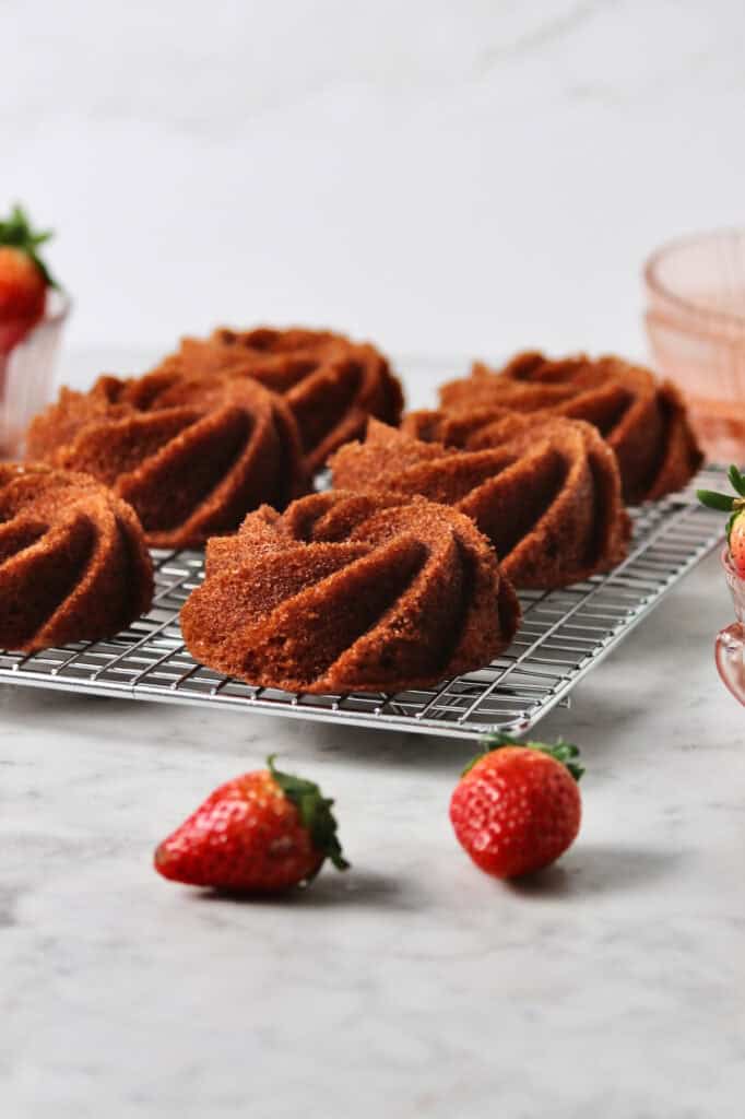 six baked strawberry bundt cakes, sitting on a cooling rack.