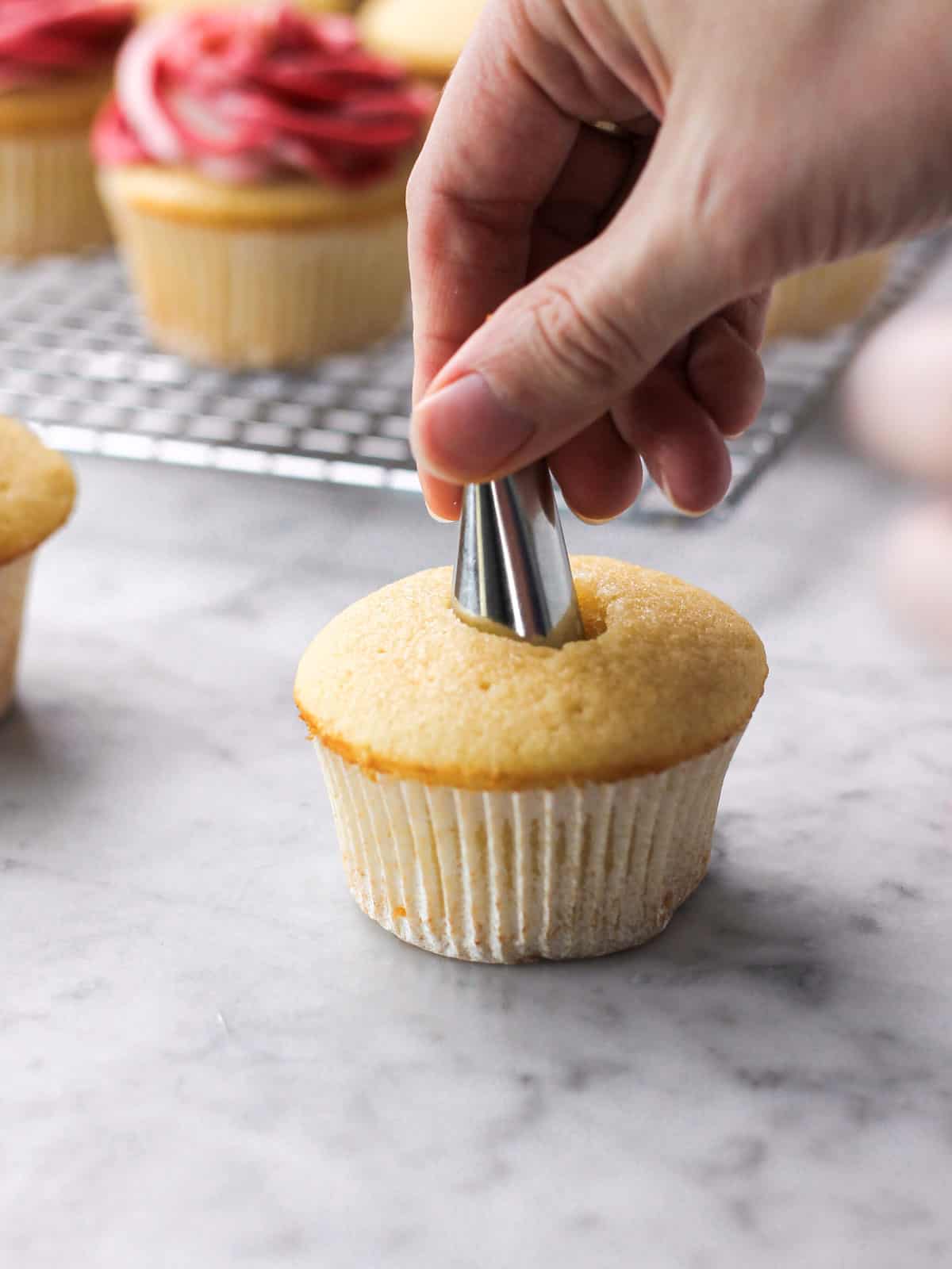 image of removing the center of a cupcake with a piping tip so filling can be added.