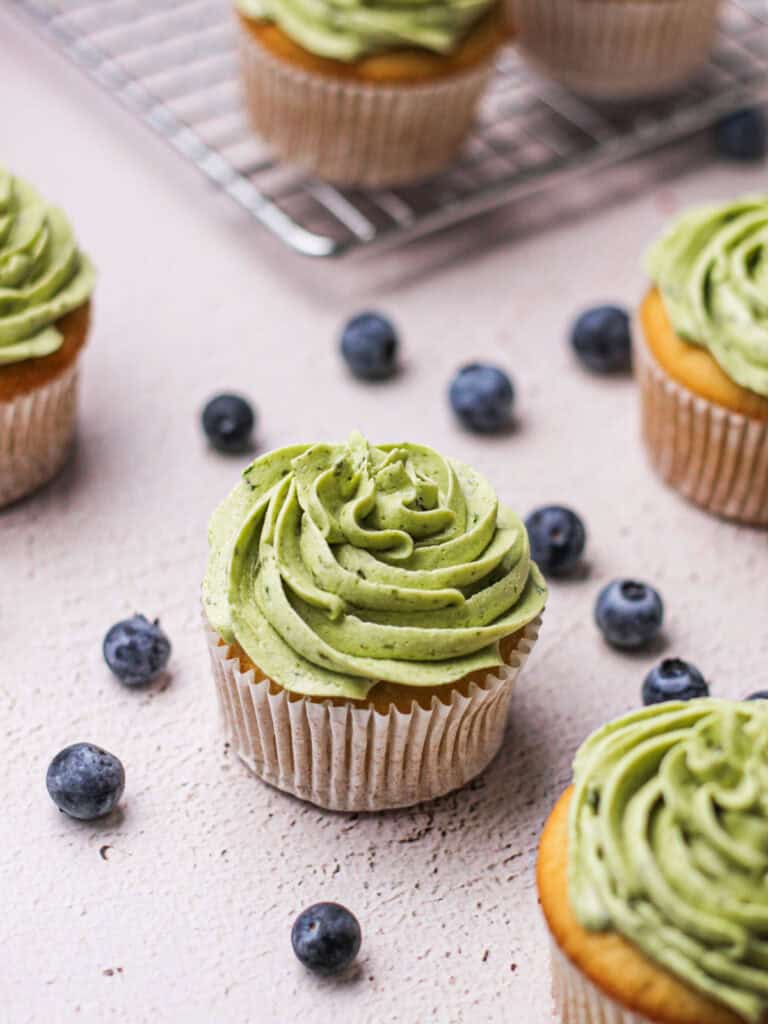 blueberry-filled cupcakes with green frosting atop them.