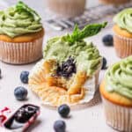 up-close shot of blueberry filled cupcakes topped with basil buttercream and a basil leaf.