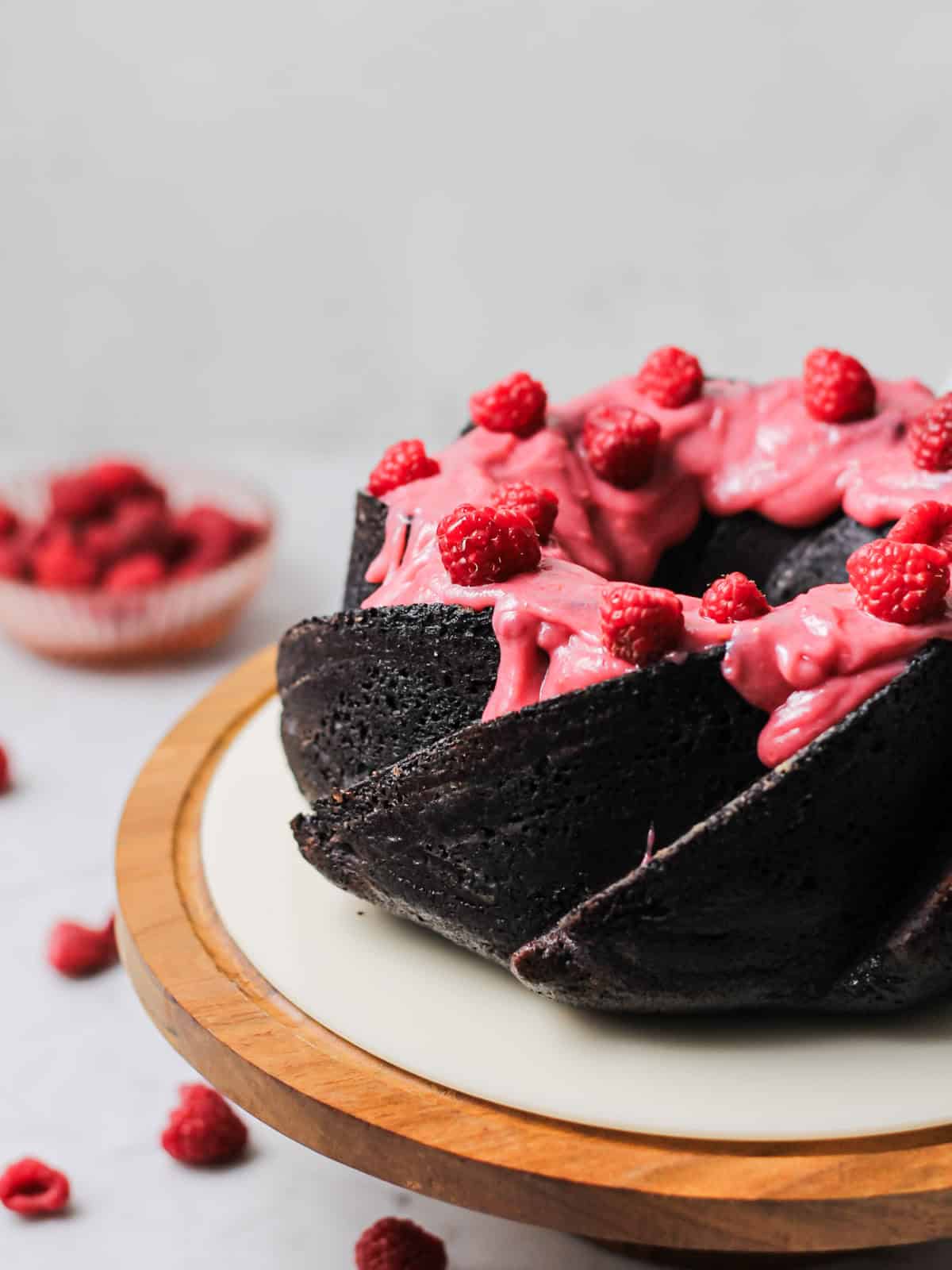 dark chocolate Bundt cake, coated with a pink raspberry cream cheese glaze and fresh raspberries on top.