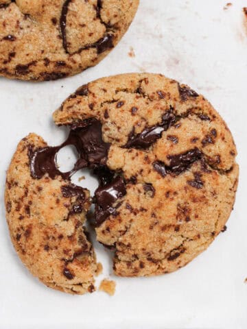 Up-close shot of one brown butter chocolate chip cookie, pulled apart to show the melted chocolate insides.