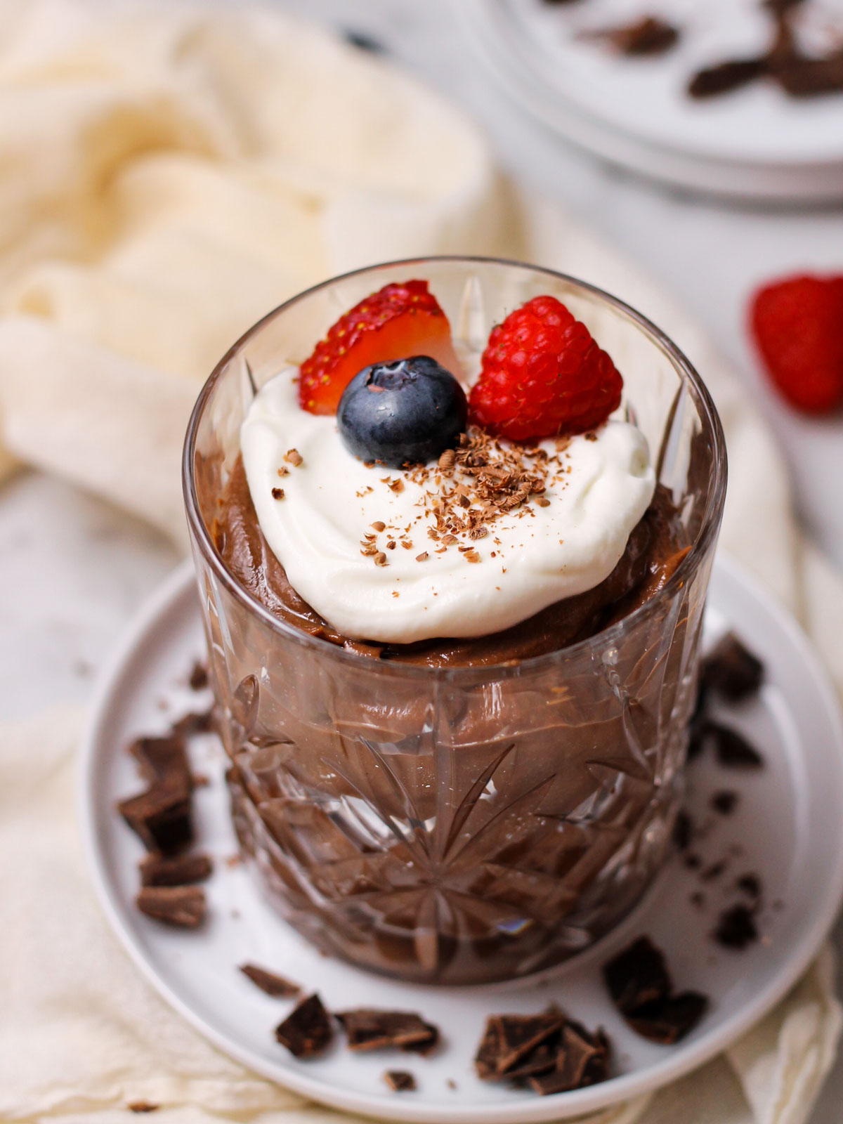 Chocolate mascarpone mousse in a small crystal glass, topped with whipped cream, chocolate shavings, and fresh berries.