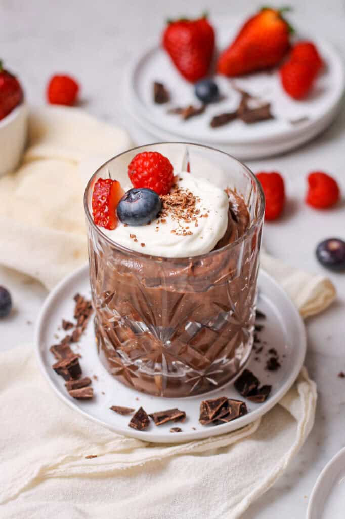 Chocolate mascarpone mousse in a small crystal glass, topped with whipped cream, chocolate shavings, and fresh berries.