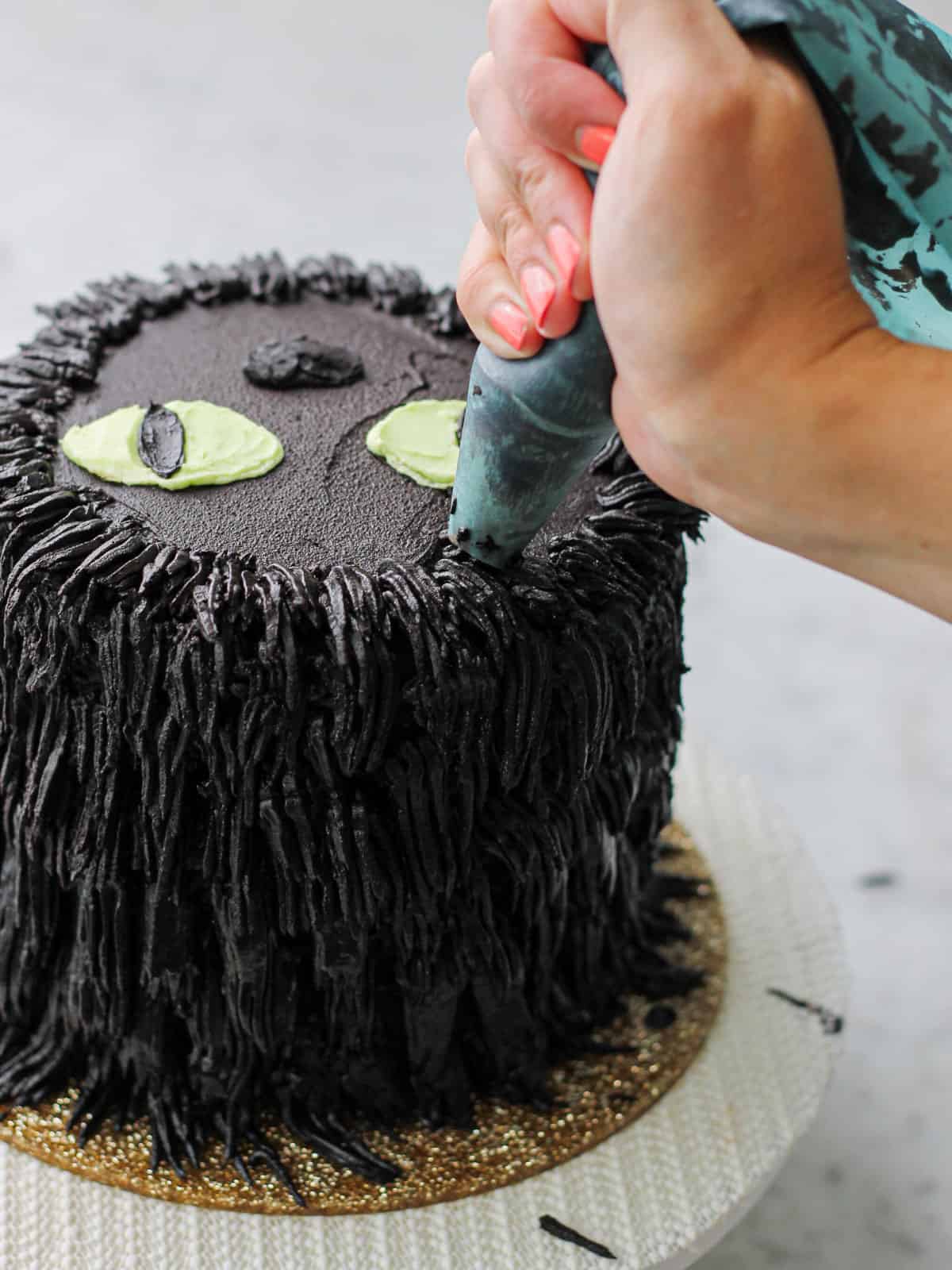 Action shot of piping black fur onto a black velvet cake with a large grass piping tip.