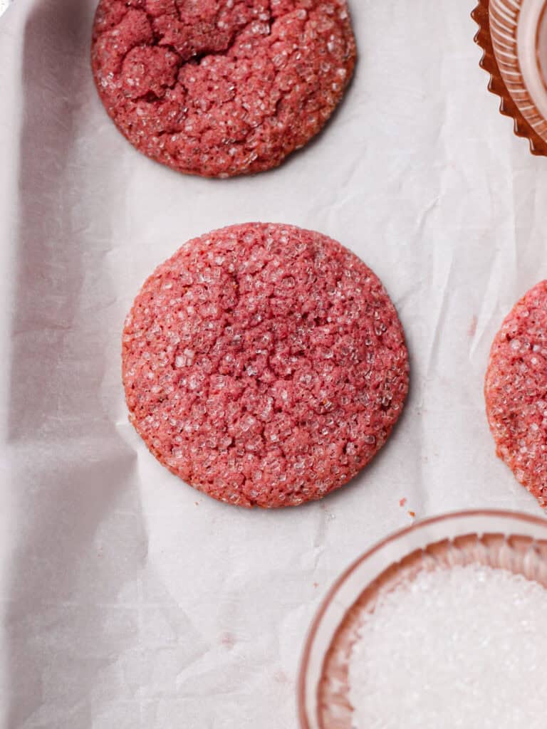 Strawberry sugar cookies, sitting on a white sheet of parchment paper after they've baked.