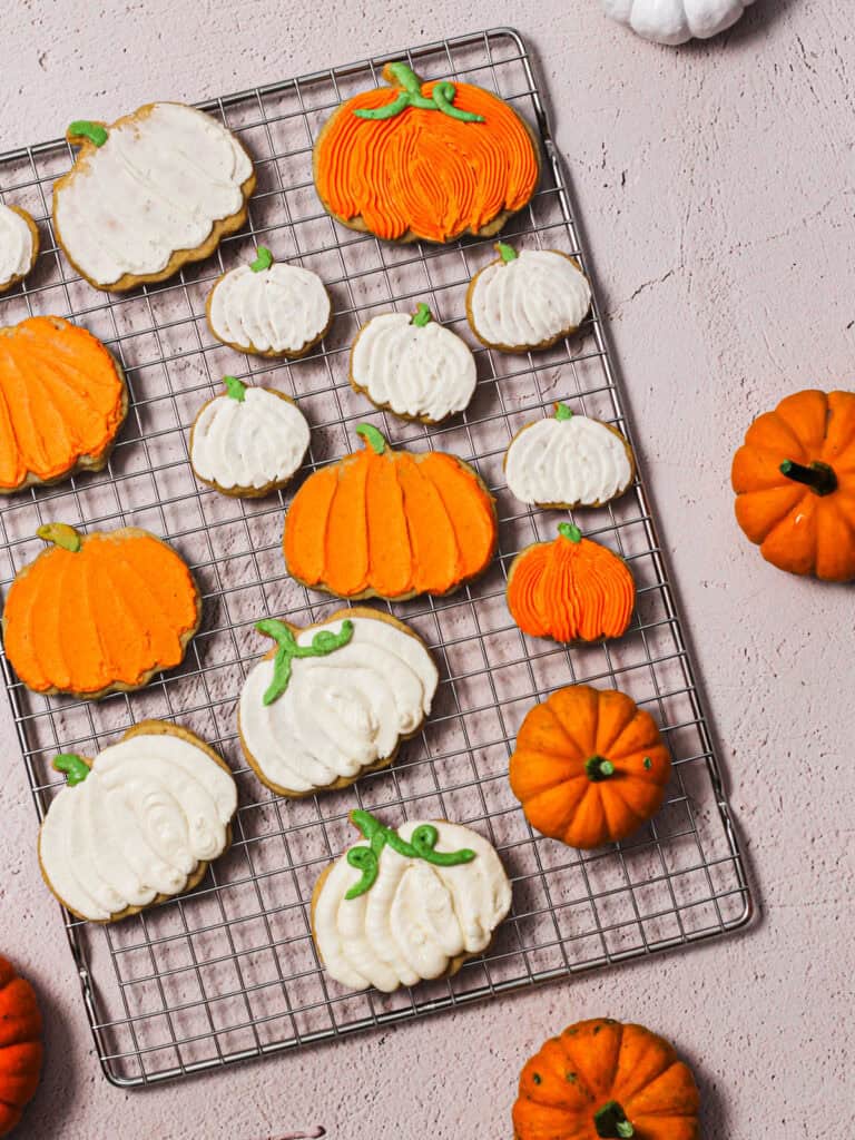 Overhead shot of baked and decorated pumpkin cookies on a cooling rack.