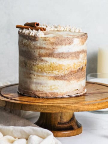 Dirty chai cake sitting on a brown cake stand with marbled chai frosting wrapped around the cake.