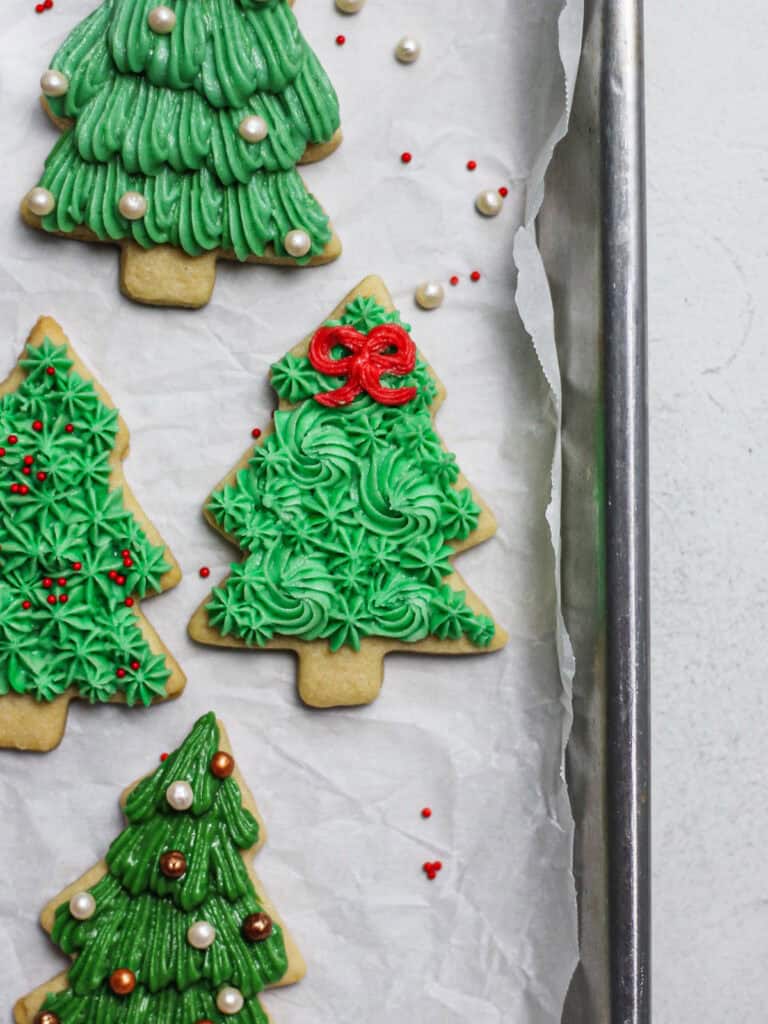 Up-close shot of Christmas tree sugar cookies, decorated with sprinkles and green buttercream.