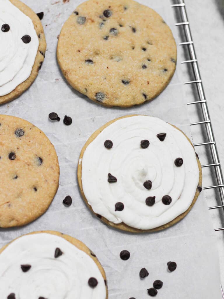 Baked and frosted cookies with chocolate chips on top.