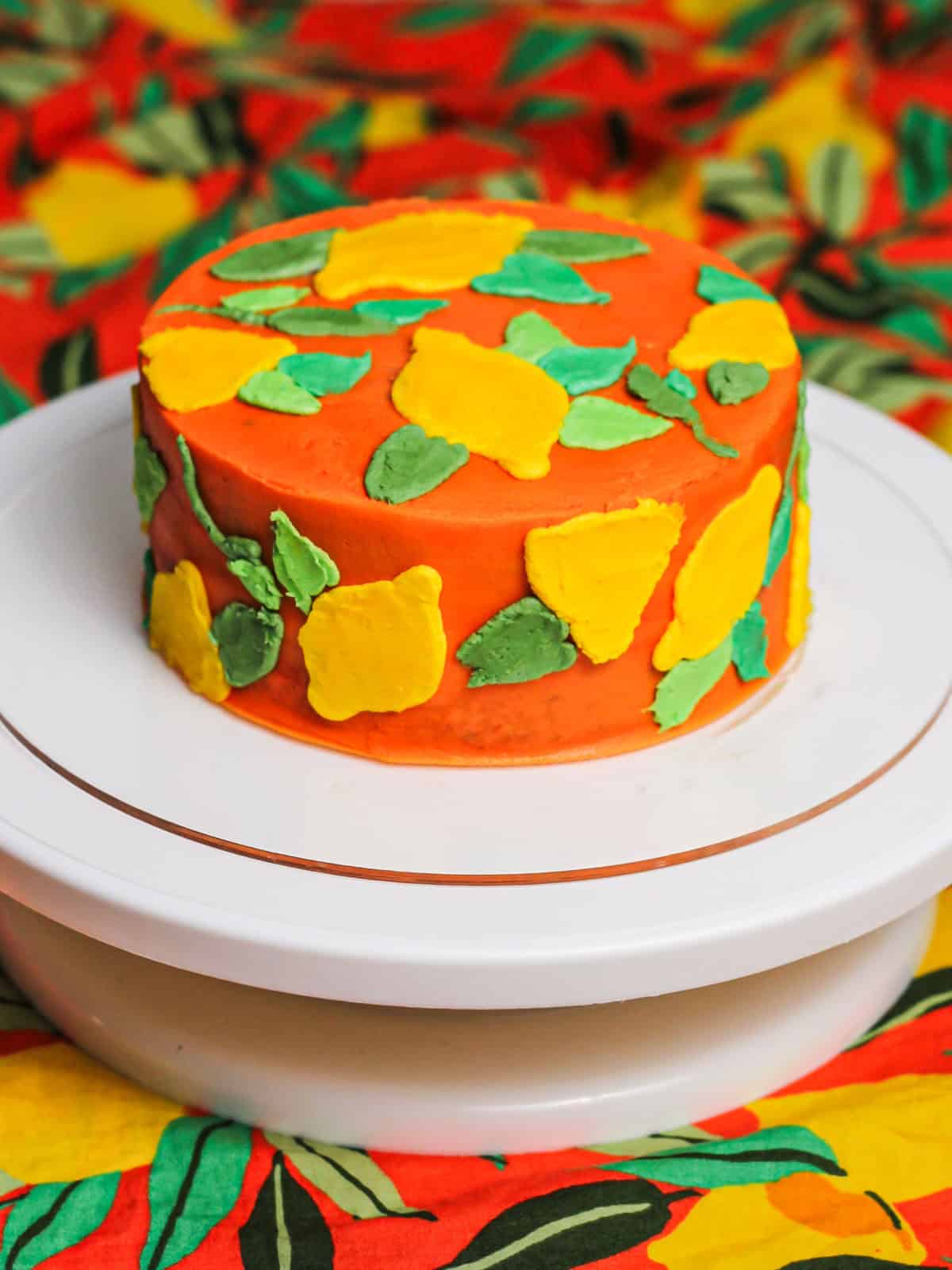 Vibrant orange layered cake decorated with colorful leaves for this buttercream lemon cake tutorial.