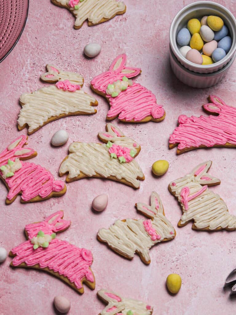 Decorated pink and white bunny cookies, sitting on a pink background.