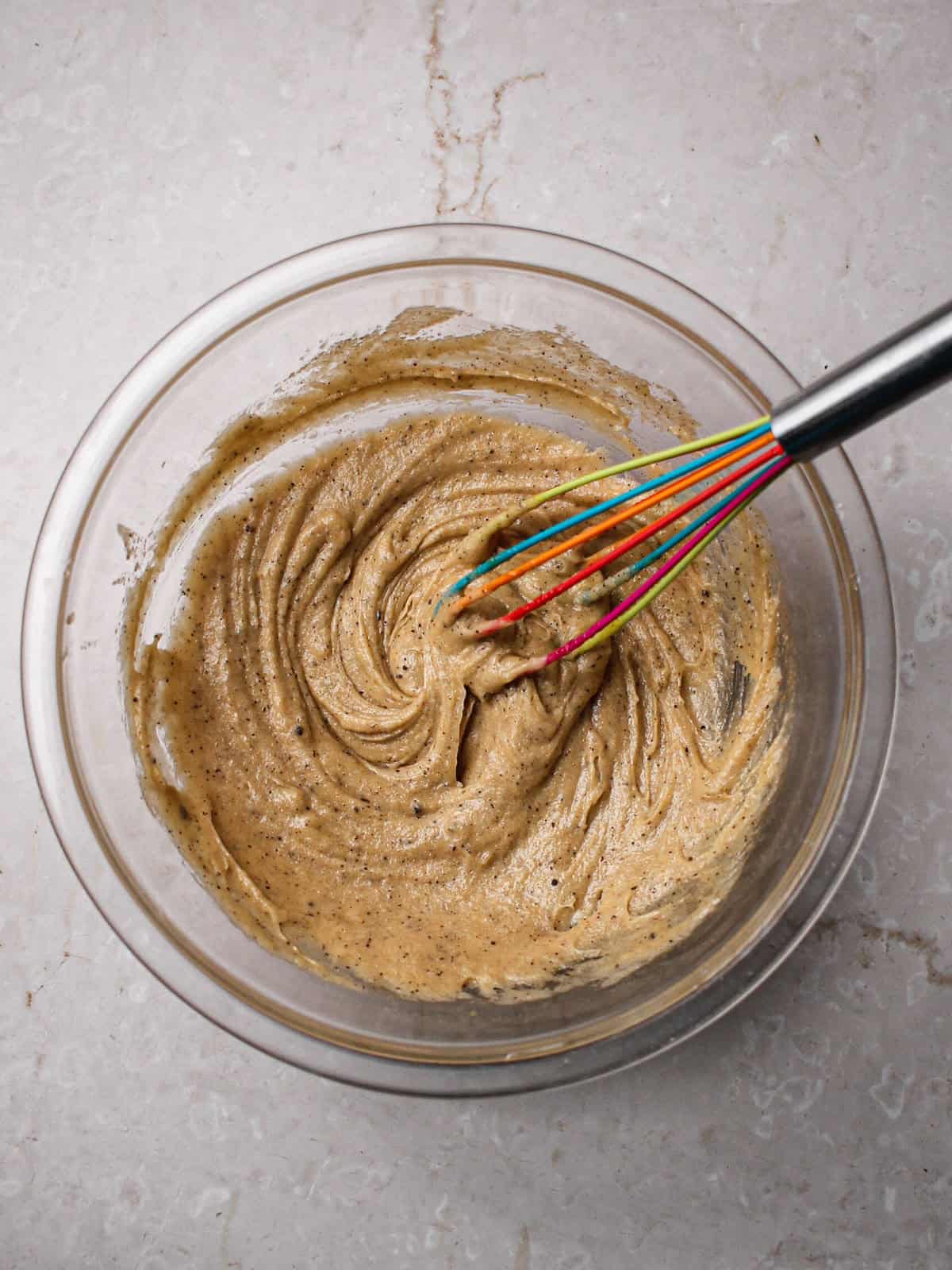 Cookie dough, with flecks of brown butter and sugars mixed together in a bowl.