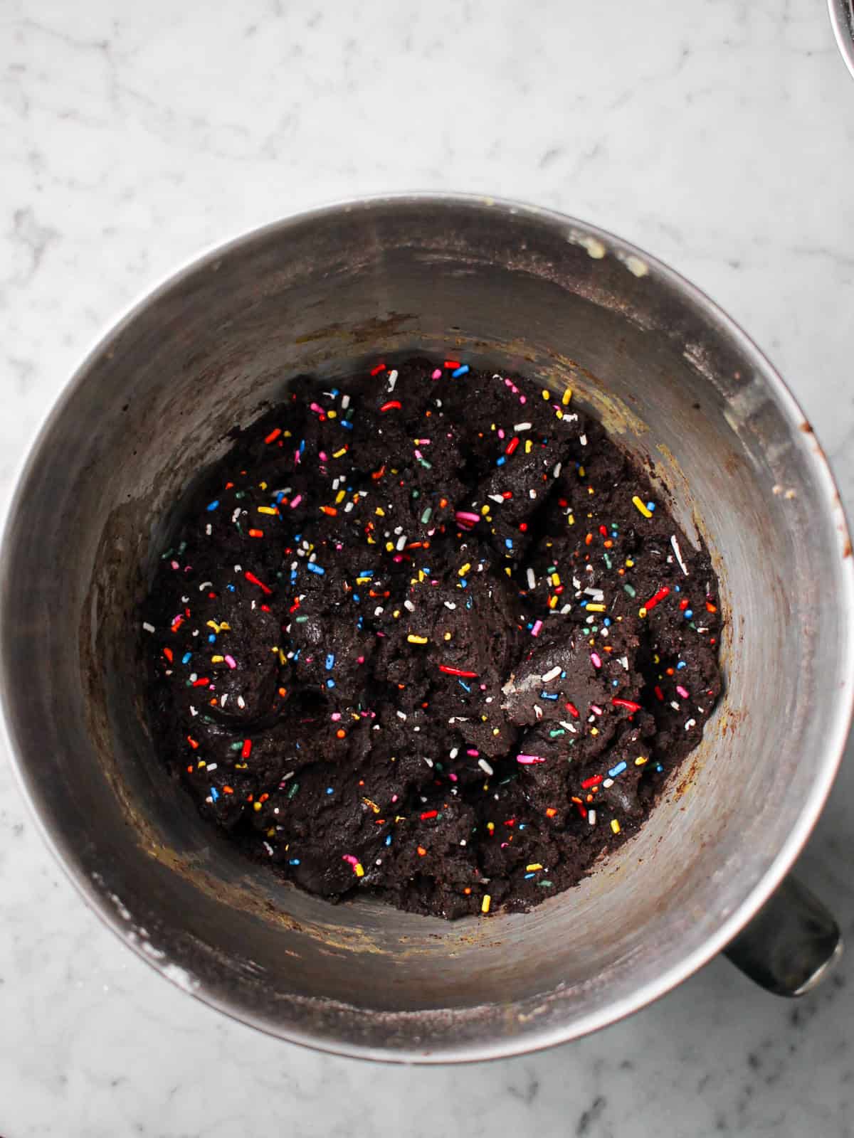 Bowl full of chocolate cookie dough with rainbow sprinkles.