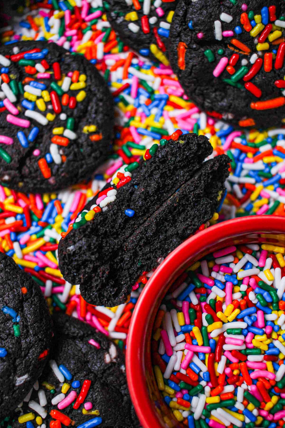 A chocolate sprinkle cookie split in half so the chewy insides are visible.