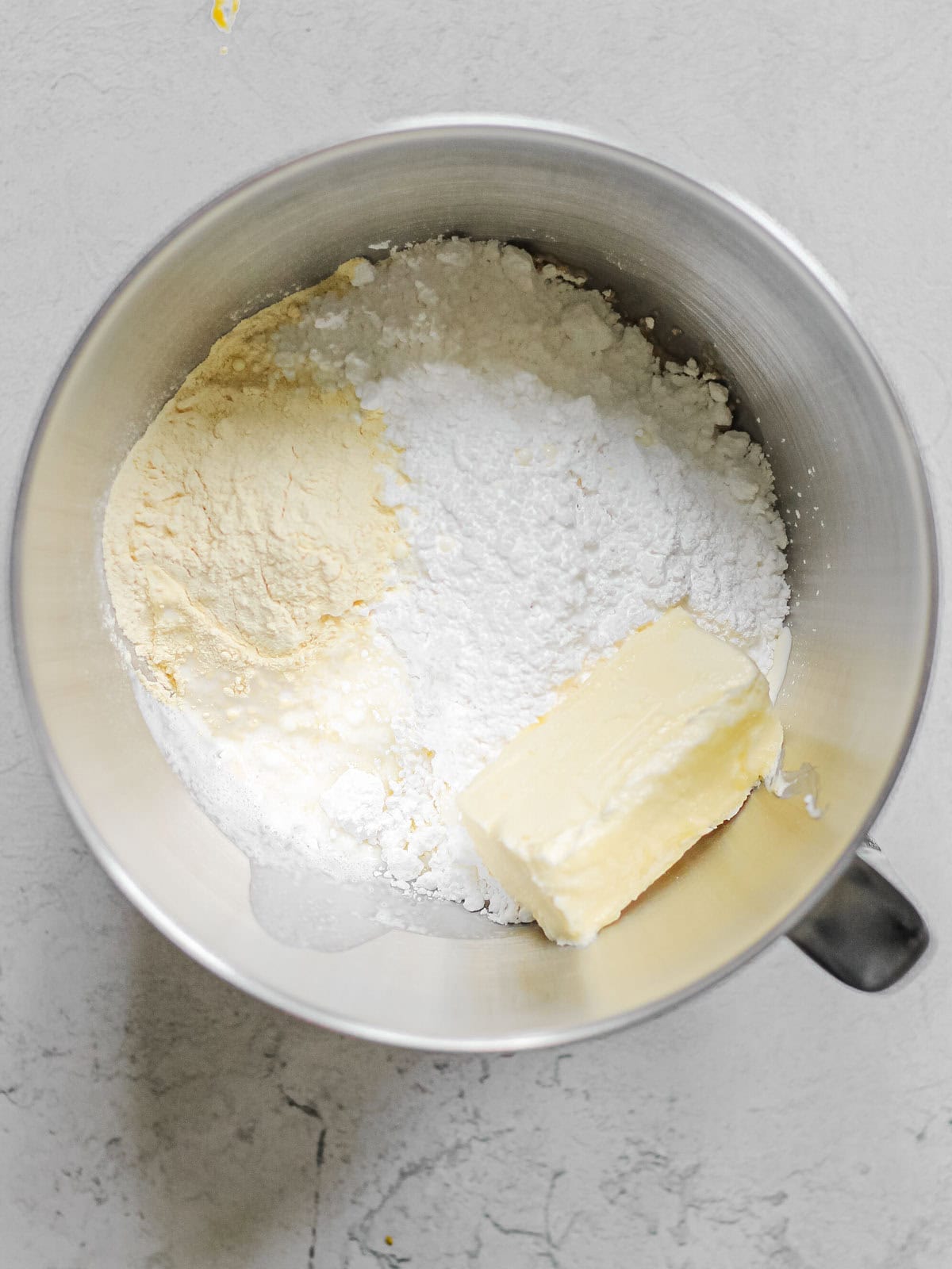 Process shot of mixing bowl, filled with ingredients for mango frosting.