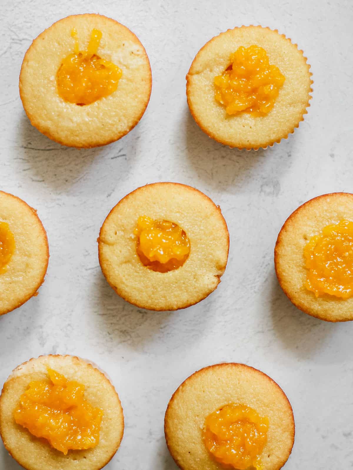 Overhead shot of vanilla cupcakes with mango filling, unfrosted, so the insides are visible.