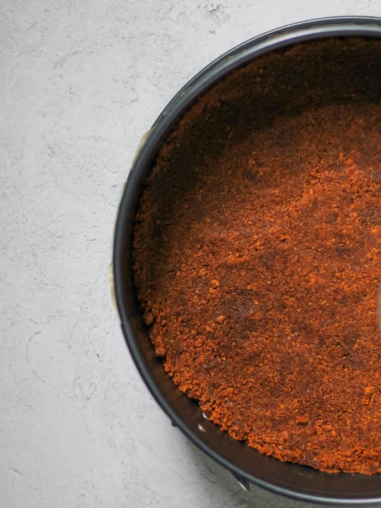 Overhead image of Biscoff Pie Crust pressed into a 9" springform pan on a grey background.