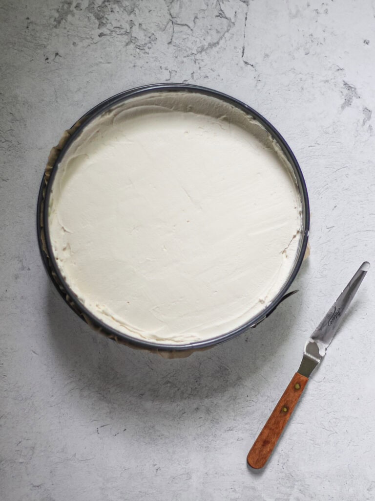 Mascarpone filling, poured into 9" springform pan, with a small offset spatula to the bottom right corner.