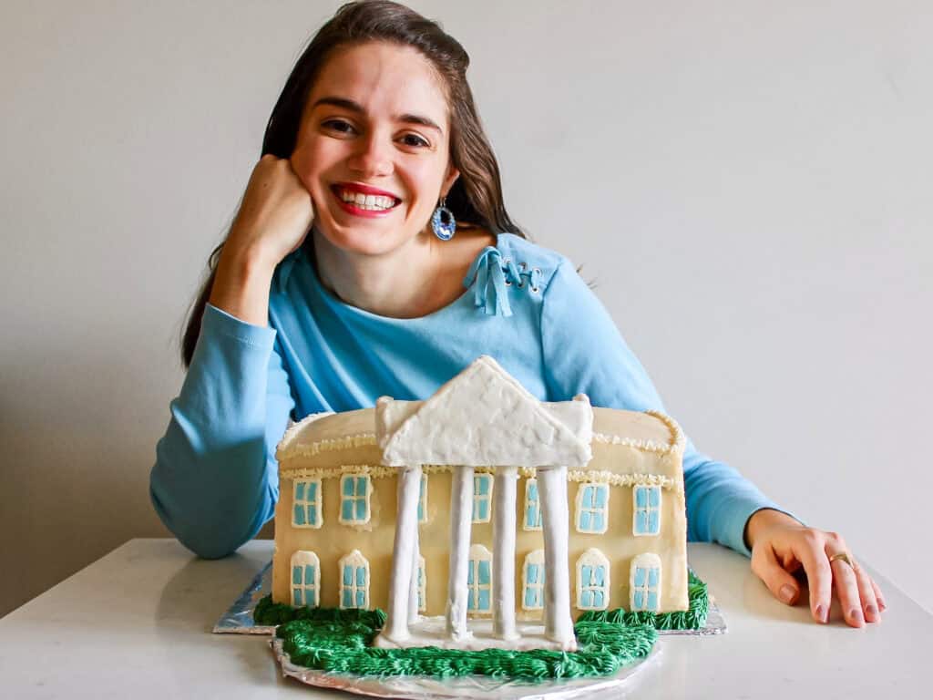 Photo of Susan, posing behind a homemade cake decorated to look like the White House.