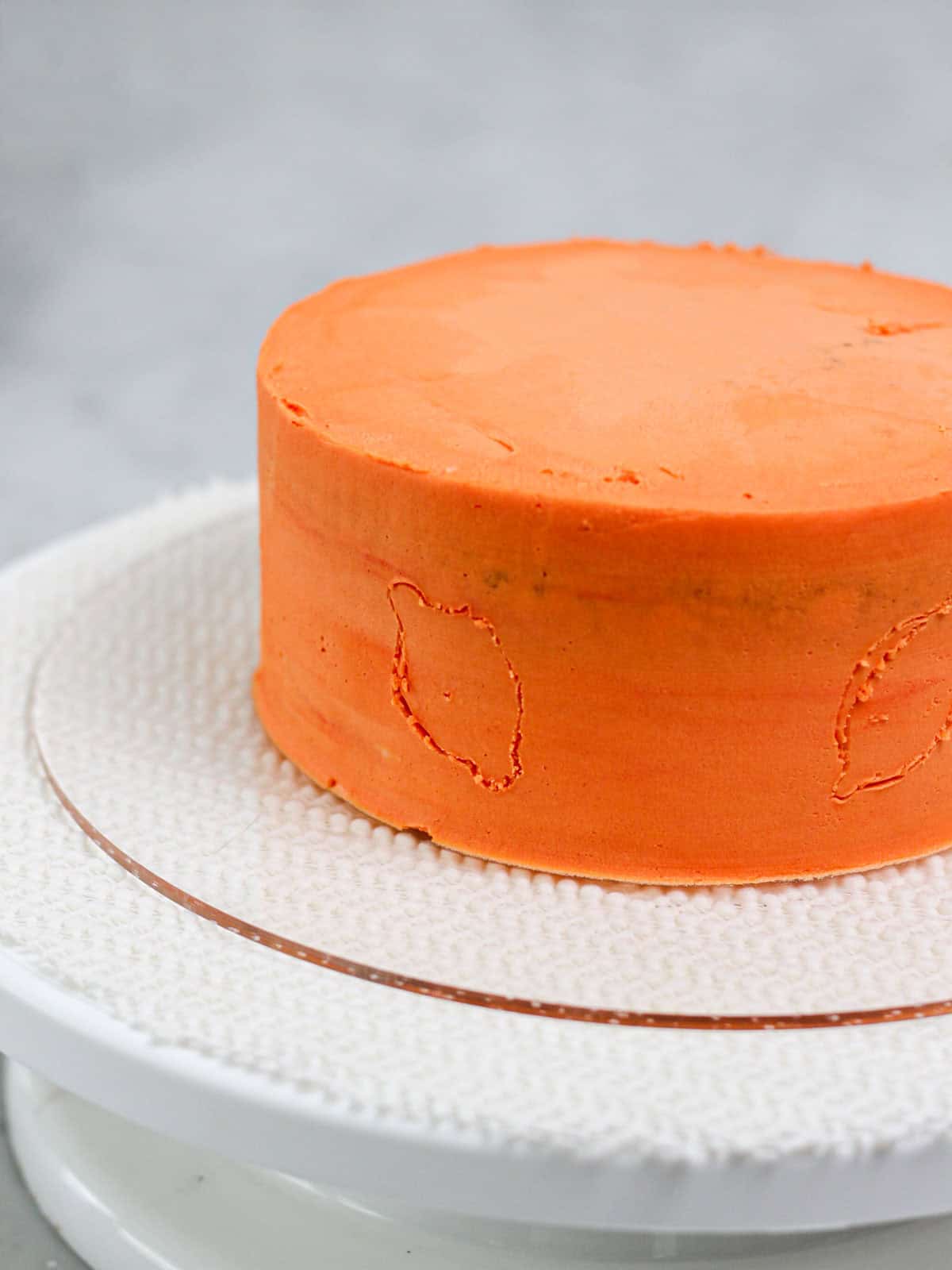 An orange cake with traced designs of lemons for this buttercream lemon cake tutorial.