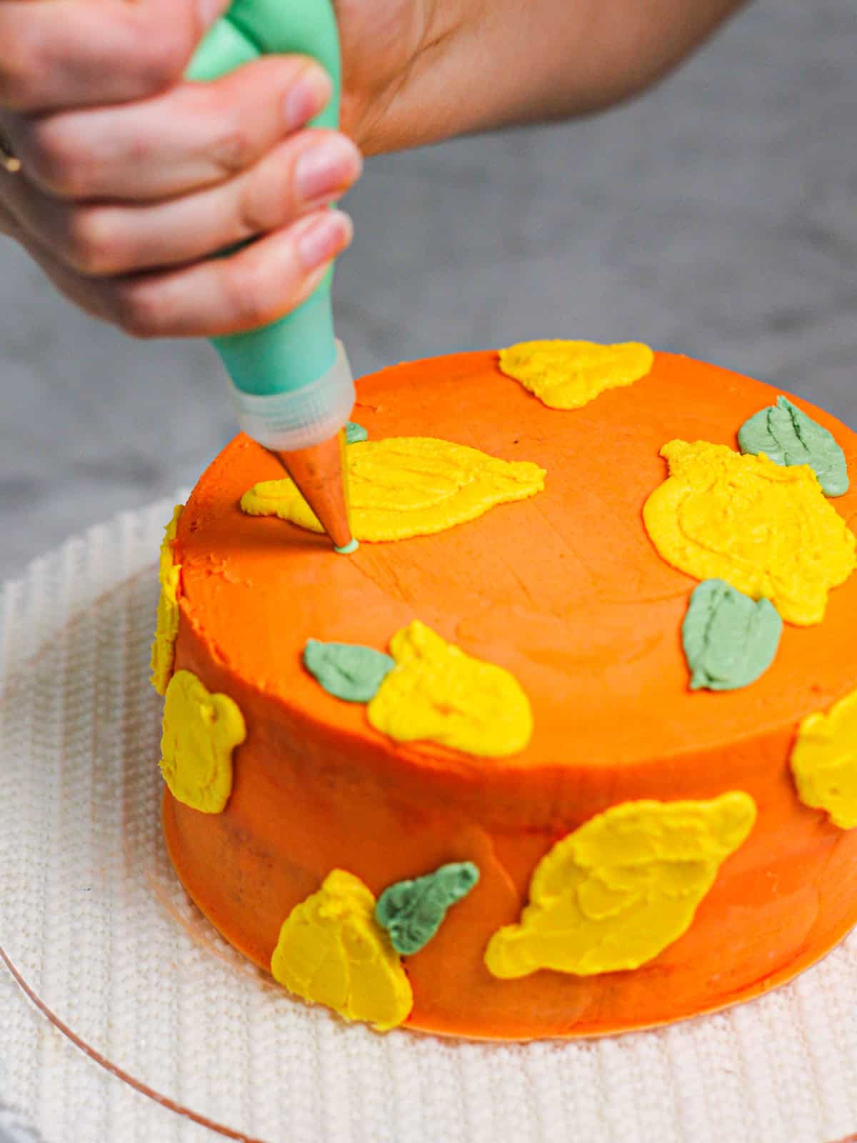 Piping green leaves onto the buttercream lemon cake.
