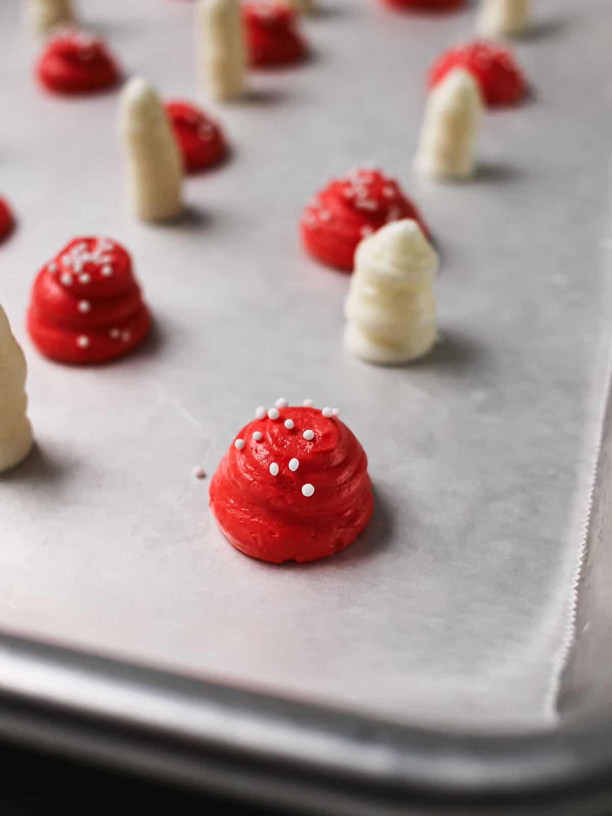 Piped mushroom caps and stems set on parchment for freezing.