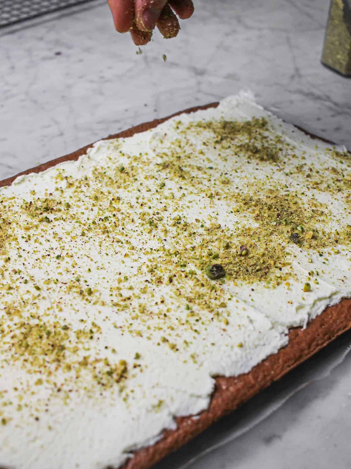 Action shot of adding pistachios to our chocolate yule log's filling.