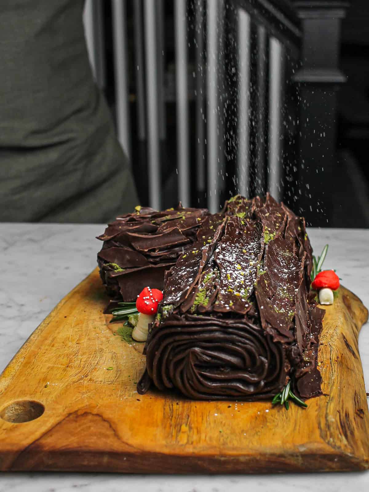 Action shot of dusting our chocolate yule log with powdered sugar.