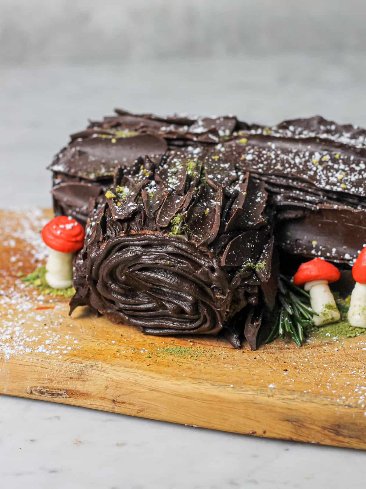 Chocolate yule log, made from a chocolate sponge and chocolate buttercream, resting on a brown cutting board.